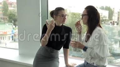 两个在银行工作的女商人在窗口喝咖啡，午餐时<strong>交流</strong>。 工作，咖啡，<strong>交流</strong>